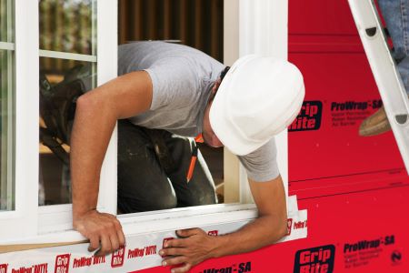 Construction worker applying Grip-Rite<sup>®</sup> flexible flashing tape to the exterior of a home